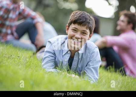 Un garçon assis sur l'herbe en été, pour un parti. Banque D'Images