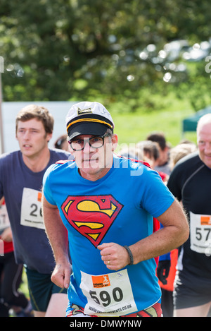 Concurrent qui traverse la ligne de départ d'un essai d'endurance /race habillés en costume de superman Derbyshire, Angleterre Banque D'Images