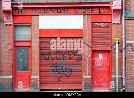 Une course vers le bas en Cheltenjam Téléphone shop UK avec portes rouges et graffiti sur elle. Banque D'Images