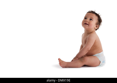 Bébé garçon assis sur le plancher sur fond blanc Banque D'Images