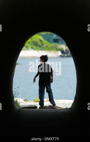 Un garçon sort d'un tunnel court le long d'une section de Cliff Walk, une attraction populaire et marcher à Newport Rhode Island Banque D'Images