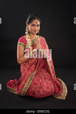 Indian girl dans un message d'accueil pose, sari traditionnel costume, pleine longueur genoux sur marbre isolé sur fond noir Banque D'Images