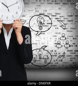 Composite image of businesswoman in suit holding a clock Banque D'Images