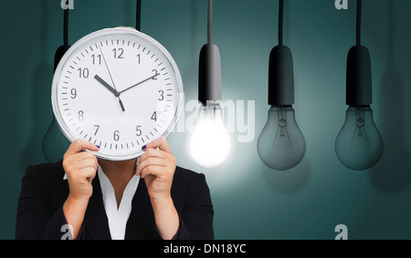 Composite image of businesswoman in suit holding a clock Banque D'Images