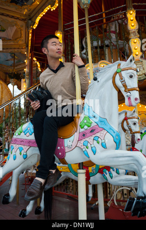 Paris, France, jeune homme d'origine chinoise, sur le français merry-go-Round, mange, Banque D'Images