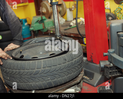 Mécanicien automobile professionnel changer un pneu in auto repair shop Banque D'Images