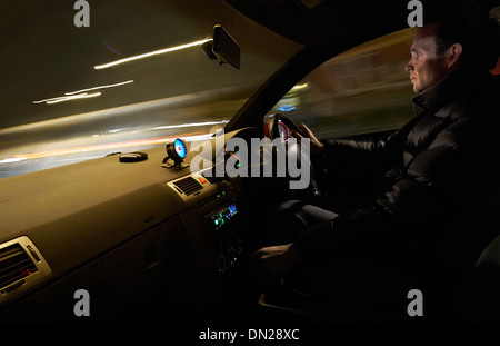 Une vue intérieure d'un homme conduisant une voiture rapide dans la nuit. Banque D'Images