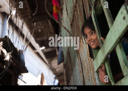 Mumbai, Inde. Dec 18, 2013. Une fille regarde par la fenêtre de sa chambre dans le bidonville de Mumbai, Inde, 18 décembre 2013. De l'autre côté de l'Inde centre économique et financier, Mumbai, il se trouve un des plus grands bidonvilles du pays. Les résidents vivent dans des salles encombrées, minable, et le craps sont vus partout. Mais la vie à Mumbai, la bidonville n'est pas tout au sujet de la pauvreté et de pessimisme, certaines personnes ont commencé à ouvrir des magasins, d'envoyer leurs enfants à l'école et de faire des affaires. Banque D'Images