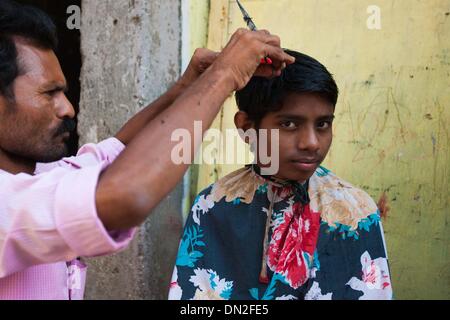 Mumbai, Inde. Dec 18, 2013. Un coiffeur coupe les cheveux pour un client dans le bidonville de Mumbai, Inde, 18 décembre 2013. De l'autre côté de l'Inde centre économique et financier, Mumbai, il se trouve un des plus grands bidonvilles du pays. Les résidents vivent dans des salles encombrées, minable, et le craps sont vus partout. Mais la vie à Mumbai, la bidonville n'est pas tout au sujet de la pauvreté et de pessimisme, certaines personnes ont commencé à ouvrir des magasins, d'envoyer leurs enfants à l'école et de faire des affaires. Banque D'Images