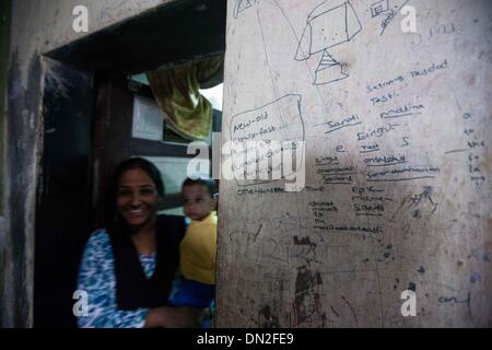 Mumbai, Inde. Dec 18, 2013. Une femme tient son bébé à la maison dans le bidonville de Mumbai, Inde, 18 décembre 2013. De l'autre côté de l'Inde centre économique et financier, Mumbai, il se trouve un des plus grands bidonvilles du pays. Les résidents vivent dans des salles encombrées, minable, et le craps sont vus partout. Mais la vie à Mumbai, la bidonville n'est pas tout au sujet de la pauvreté et de pessimisme, certaines personnes ont commencé à ouvrir des magasins, d'envoyer leurs enfants à l'école et de faire des affaires. Banque D'Images