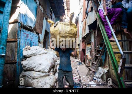 Mumbai, Inde. Dec 18, 2013. Un homme porte un sac d'ordures pour recycler station dans le bidonville de Mumbai, Inde, 18 décembre 2013. De l'autre côté de l'Inde centre économique et financier, Mumbai, il se trouve un des plus grands bidonvilles du pays. Les résidents vivent dans des salles encombrées, minable, et le craps sont vus partout. Mais la vie à Mumbai, la bidonville n'est pas tout au sujet de la pauvreté et de pessimisme, certaines personnes ont commencé à ouvrir des magasins, d'envoyer leurs enfants à l'école et de faire des affaires. Banque D'Images