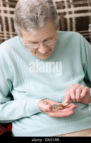 Vieille Femme tenant un mélange de pièces (en passant par de l'argent à l'ère d'austérité) Banque D'Images