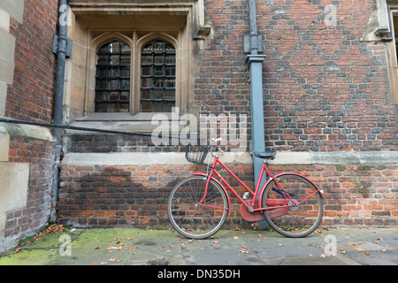 Un vélo rouge garée contre un mur à Cambridge UK Banque D'Images