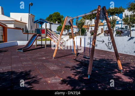 Une aire de jeux pour enfants avec toboggans et balançoires avec graffito sur le mur, Banque D'Images