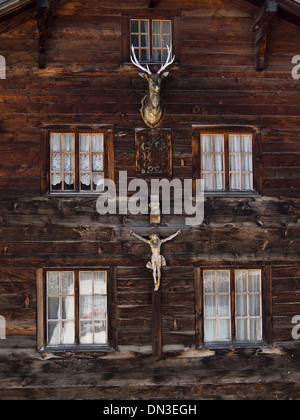 Vieux bois traditionnel en bois typique façade de maison avec windows, cerfs tête et crucifix le Munster village Suisse Banque D'Images