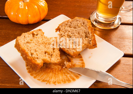 Muffin coupé en deux sur une plaque avec une tasse de thé et une citrouille Banque D'Images