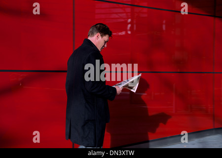 Businessman reading le Métro sur fond rouge Banque D'Images