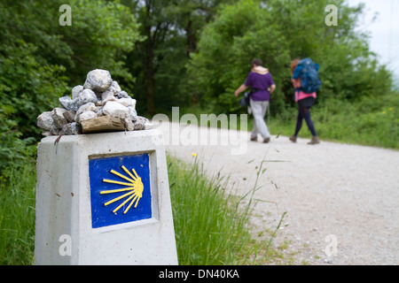 Les Pèlerins à pied près d'un marqueur le long du Camino de Santiago, le Chemin de Saint-Jacques de Compostelle, Navarra, Espagne. Banque D'Images