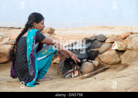 Femme indienne au chaud par un feu ouvert dans un village de l'Inde rurale. L'Andhra Pradesh, Inde Banque D'Images