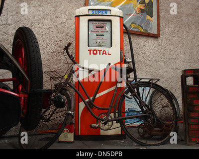 Une vieille pompe à essence, de marque total, se tient avec un vélo garé devant elle. L'image capture une scène nostalgique, mettant en évidence une pompe à carburant vintage du passé, évoquant des souvenirs d'une ère antérieure des transports et des stations-service. Banque D'Images