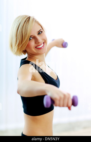 Closeup portrait of a young woman holding dumbbells Banque D'Images