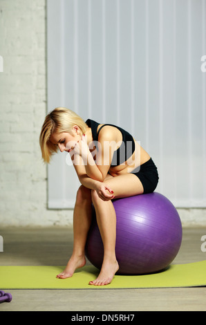 Les jeunes pensive fit woman sitting on the fitball Banque D'Images