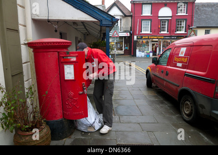 Un travailleur des postes de vider un sac de courrier dans une boîte postale rouge à côté d'un bureau de poste van Llandovery Wales UK KATHY DEWITT Banque D'Images