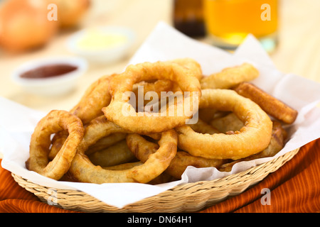 La bière fait maison fraîchement préparé-battered onion rings dans un panier avec des boissons et des sauces à l'arrière Banque D'Images