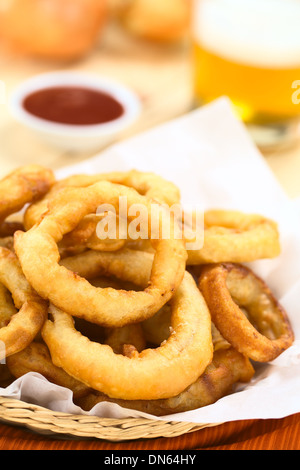 La bière fait maison fraîchement préparé-battered onion rings dans un panier avec de la bière et du ketchup à l'arrière Banque D'Images