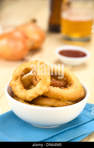 La bière fait maison fraîchement préparé-battered onion rings dans un bol avec de la bière, du ketchup et les oignons dans le dos Banque D'Images