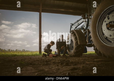 Portrait père et fils travaillant sur le tracteur Banque D'Images