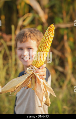 Caucasian boy holding ear of corn on farm Banque D'Images