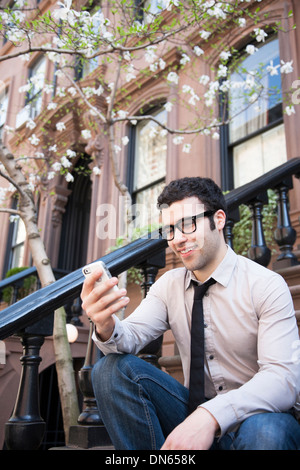 Hispanic businessman using cell phone on marches Banque D'Images