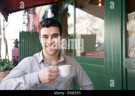 Hispanic man sitting at sidewalk cafe Banque D'Images