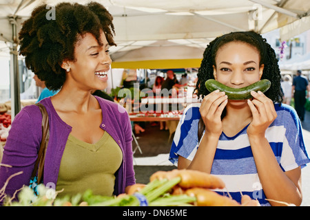 Women smiling together at outdoor market Banque D'Images