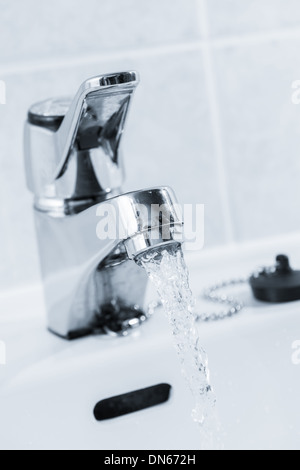 Ouvrir le robinet dans la salle de bain, l'eau est en cours d'exécution, teinté en noir et blanc, format vertical Banque D'Images