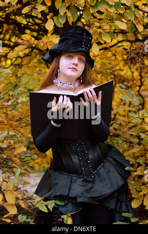 Cos-joueur avec un livre dans le parc en automne Banque D'Images