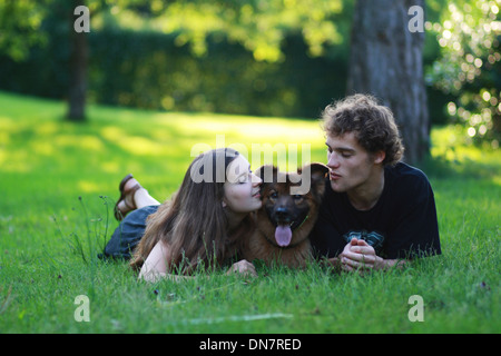 Jeune couple avec un chien couché sur un pré Banque D'Images