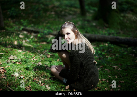 Fille accroupie sur le sol forestier, portrait Banque D'Images