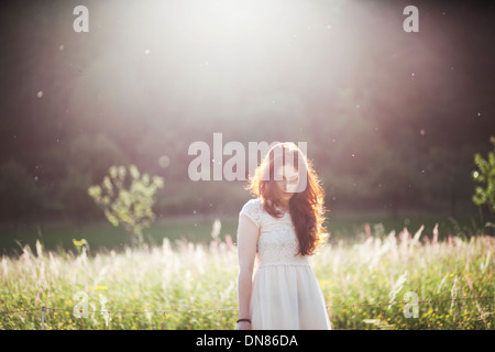 Jeune femme debout sur une prairie en contre-jour, portrait Banque D'Images