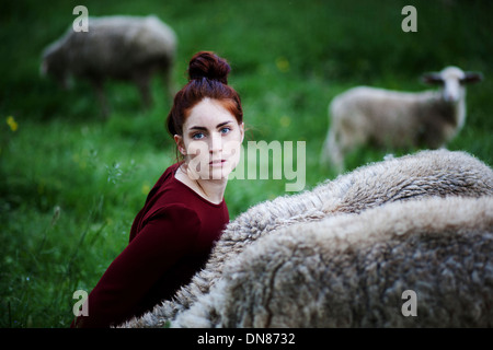 Jeune femme avec des moutons dans un pré Banque D'Images