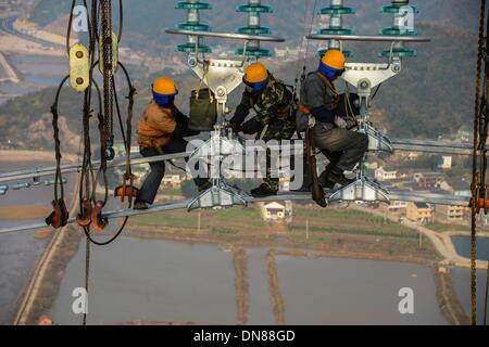 Zhoushan, Chine, Province de Zhejiang. 18Th Oct, 2013. Les électriciens travaillent sur les lignes de transmission de plus de 190 mètres au-dessus du sol à Hefei, Chine de l'est la province du Zhejiang, le 19 décembre 2013. La croix de 500 kilovolts-sea power transmission projet devrait mettre en service en janvier 2014. Les 36,5 kilomètres de long projet, dont 8,39 kilomètres de mer, a été la plus longue de ce type en Chine jusqu'à présent. © Xu Yu/Xinhua/Alamy Live News Banque D'Images