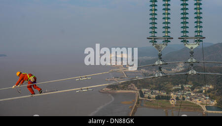 Zhoushan, Chine, Province de Zhejiang. 18Th Oct, 2013. Un électricien inspecte les lignes de transmission de plus de 190 mètres au-dessus du sol à Hefei, Chine de l'est la province du Zhejiang, le 19 décembre 2013. La croix de 500 kilovolts-sea power transmission projet devrait mettre en service en janvier 2014. Les 36,5 kilomètres de long projet, dont 8,39 kilomètres de mer, a été la plus longue de ce type en Chine jusqu'à présent. © Xu Yu/Xinhua/Alamy Live News Banque D'Images