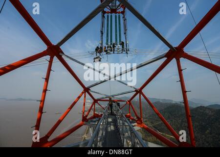 Zhoushan, Chine, Province de Zhejiang. 18Th Oct, 2013. Les électriciens travaillent sur les lignes de transmission de plus de 190 mètres au-dessus du sol à Hefei, Chine de l'est la province du Zhejiang, le 19 décembre 2013. La croix de 500 kilovolts-sea power transmission projet devrait mettre en service en janvier 2014. Les 36,5 kilomètres de long projet, dont 8,39 kilomètres de mer, a été la plus longue de ce type en Chine jusqu'à présent. © Xu Yu/Xinhua/Alamy Live News Banque D'Images