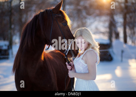 Jeune femme en robe blanche à cheval en hiver Banque D'Images