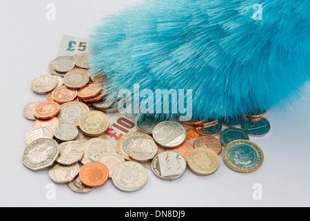 Un plumeau poussière une pile de pièces et billets de l'argent sterling. En Angleterre, Royaume-Uni, Angleterre Banque D'Images