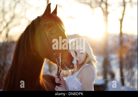 Jeune femme en robe blanche à cheval en hiver