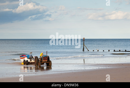 Un pêcheur de conduire un tracteur Ford, son remorquage bateau de pêche de la mer à Cromer, Norfolk, Angleterre, Royaume-Uni Banque D'Images