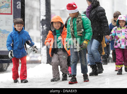 Vancouver, Canada. 18Th Oct, 2013. Les enfants marcher dans la rue avec de la neige dans le centre-ville de Vancouver, Canada, le 20 décembre 2013. Metro Vancouver a été recouvert de neige le vendredi. En raison du mauvais temps, certains accueil vols et trafic local retardé leur horaire. Les écoles annulé leurs classes. Credit : Liang Sen/Xinhua/Alamy Live News Banque D'Images