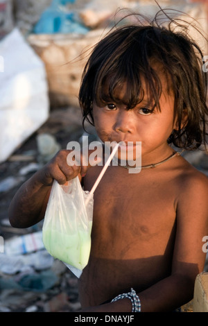 Un jeune enfant travailleur girl est en train de boire un rafraîchissement dans un dépotoir à la décharge de Stung Meanchey à Phnom Penh, Cambodge. Banque D'Images